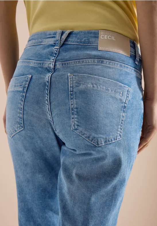 Vue de dos d'une personne portant un jean bleu clair avec étiquette de marque à la taille.