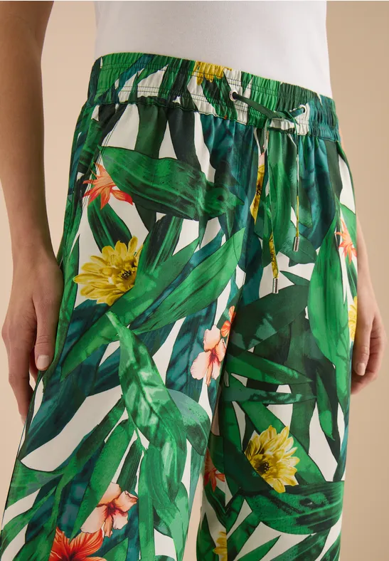 Leichte, weite Sommerhose mit grünem Blatt- und gelbem Blumenprint und Taillenschnürung.