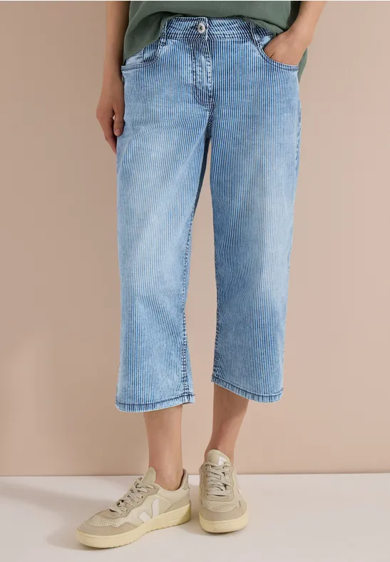 Helle, weit geschnittene 7/8-Jeans kombiniert mit beigen Sneakern.