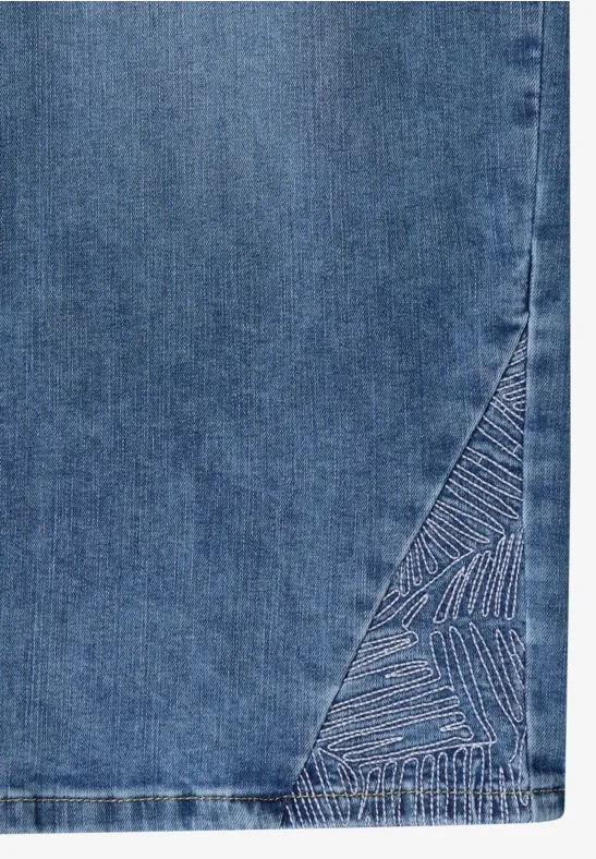 Ein Teil eines blauen Denimrocks mit gesticktem, dreieckigem Muster am Saum.