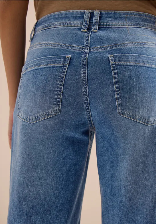 Nahaufnahme einer Person von hinten in lockeren blauen Jeans mit aufgesetzten Gesäßtaschen.