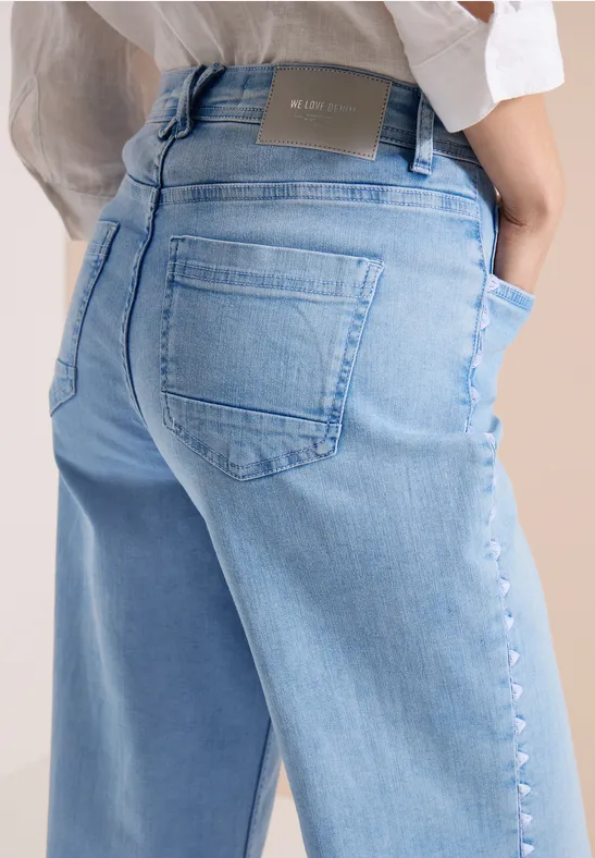 Nahaufnahme von Rücken und Hüfte einer Person in hellblauen Jeans.