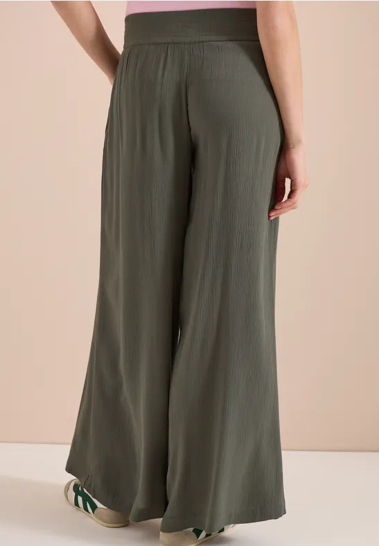 Rückansicht einer Person in olivgrünen, weit geschnittenen, fließenden Highwaist-Hose.