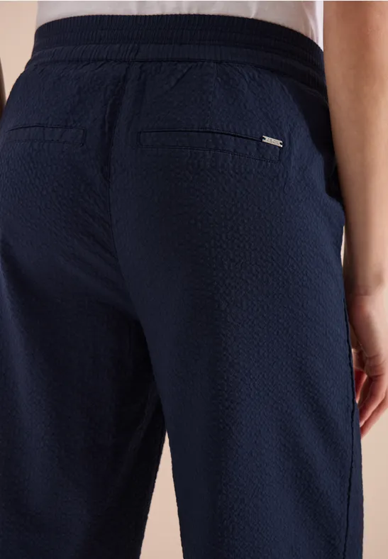 Achteraanzicht van een donkerblauwe, gestructureerde broek met achterzakken en elastische taille.