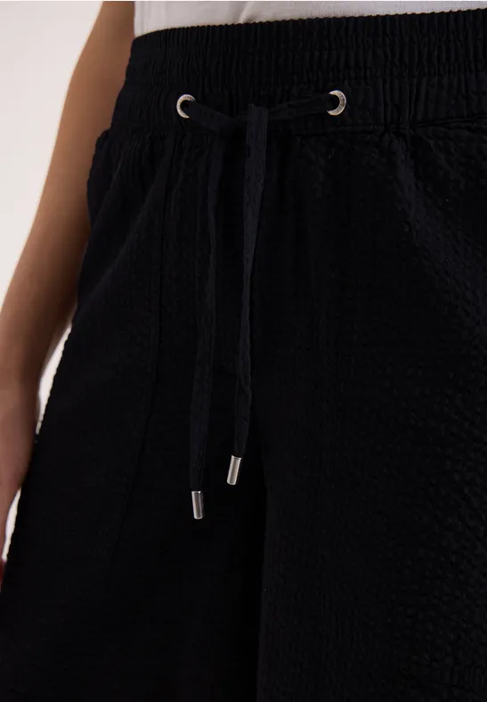 Schwarze, strukturierte Hose mit Kordelzugbund und Seitentaschen.
