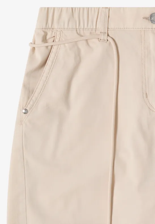 Lichtbeige broek van stof met elastische tailleband en zijzak.