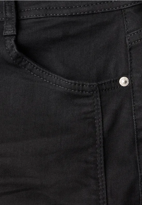 Nahaufnahme einer schwarzen Jeans mit sichtbarer Tasche, Naht und Metallniete.