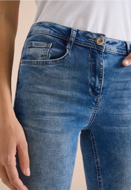 Nahaufnahme einer Person mit blauen Jeans und weißem Shirt, Hand an der Hüfte.