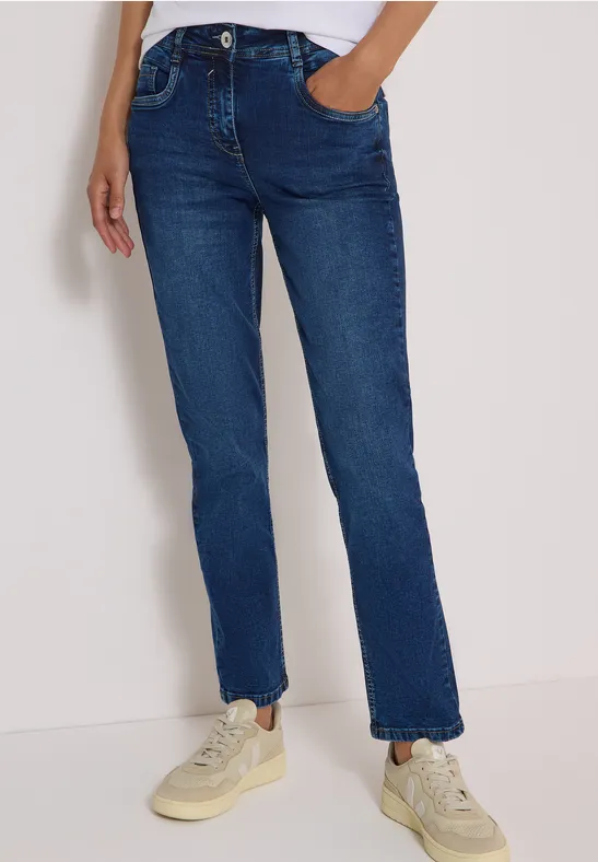 Blaue Straight-Fit-Jeans mit mittlerer Taille und Sneakers, Hand in Tasche.