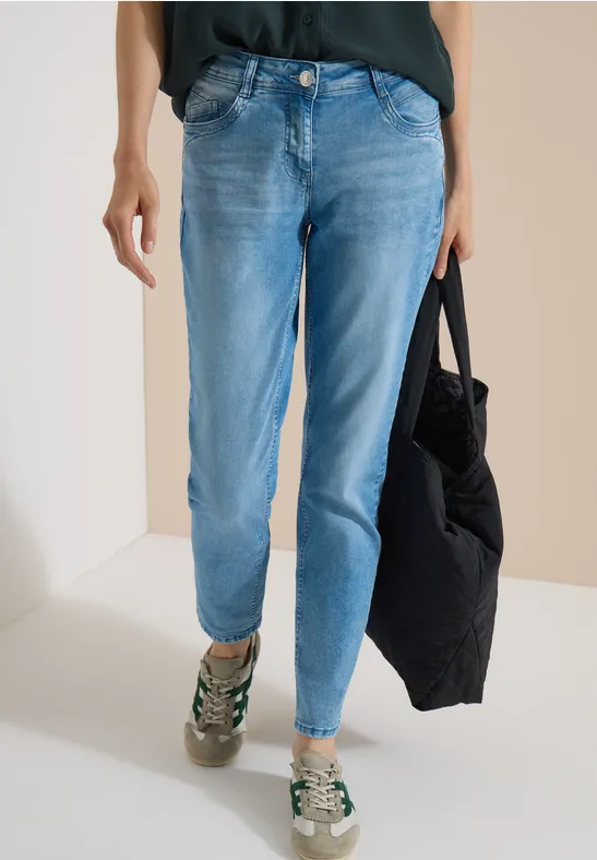 Bas du corps en jean bleu clair, baskets et sac noir.