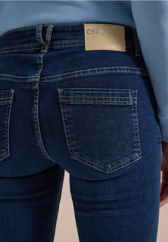Rückenansicht einer Person in engen blauen Jeans mit aufgesetzten Taschen und Lederpatch am Bund.