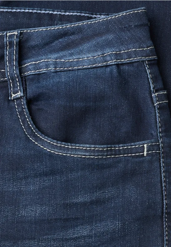 Close-up van een donkerblauw spijkerbroekzakje met witte contrasterende stiksels.