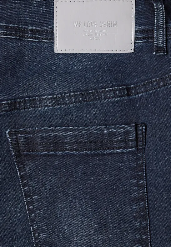 Donkerblauwe spijkerbroek met achterzak en licht lederen label in de taille.
