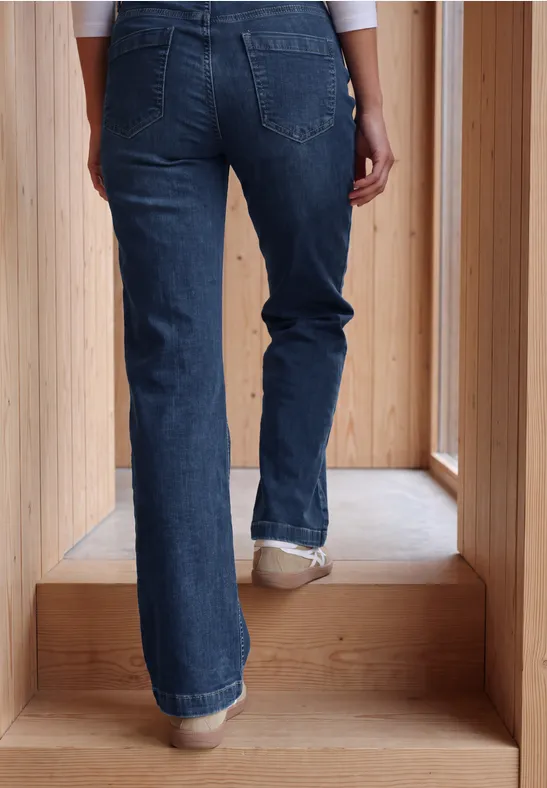Person in Jeans steigt eine helle Holztreppe hinauf, Rückenansicht bis zur Taille sichtbar.