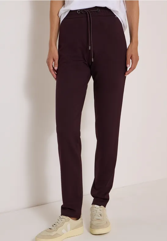 Pantalon de jogging bordeaux avec cordon, t-shirt blanc et baskets claires.