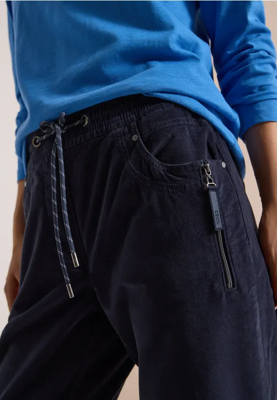 Dunkelblaue Cord-Jogginghose mit Kordelzug und Reißverschlusstaschen, kombiniert mit blauem Shirt.