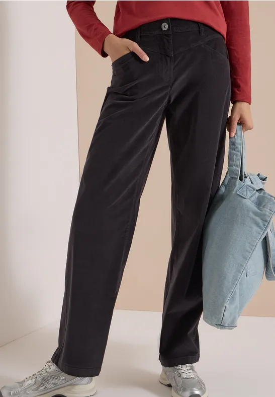 Noir pantalon droit, haut rouge à manches longues, baskets argentées et sac en tissu bleu clair.
