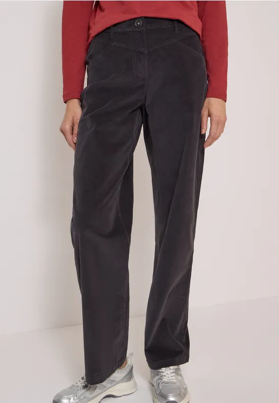 Pantalon droit en velours côtelé noir, taille haute, associé à un haut rouge et des baskets blanches.