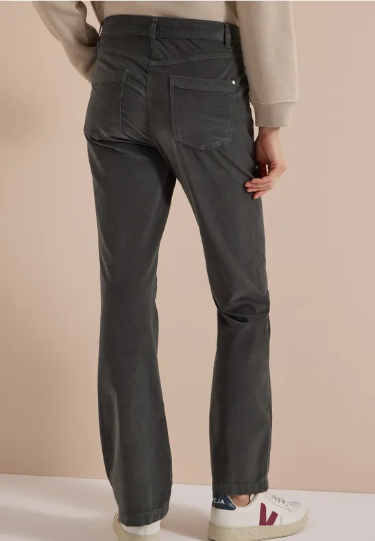 Personne de dos portant un jean gris foncé droit et des baskets blanches.