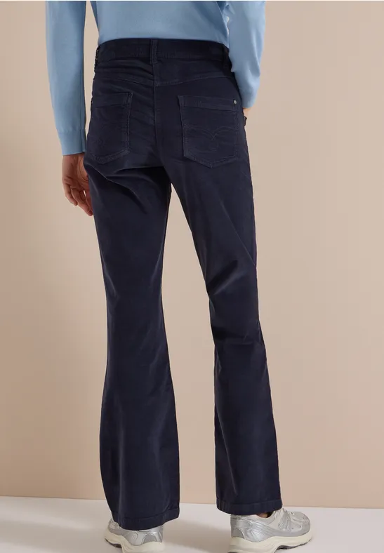 Vue arrière d'une personne en haut à manches longues bleu clair et pantalon évasé bleu foncé.