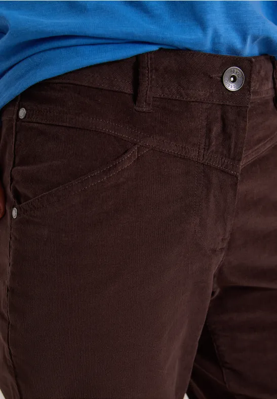 Close-up: Person trägt dunkelbraune Cordhose und ein blaues T-Shirt, Blick auf Bund und Tasche.
