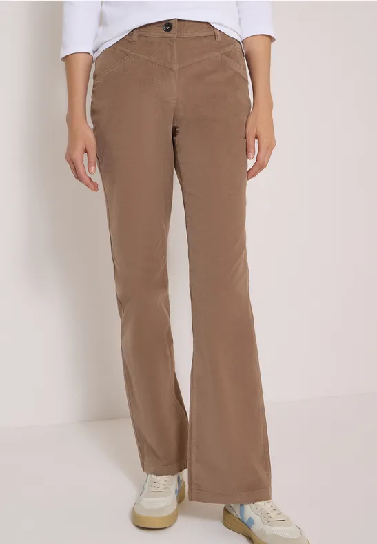 Pantalon en velours côtelé marron évasé à taille haute, porté avec des baskets blanches.