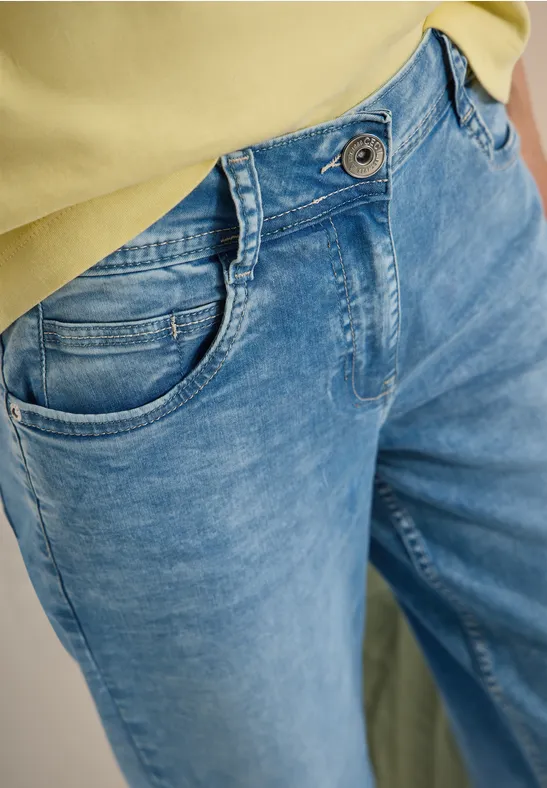 Blaue Jeans mit Vordertaschen und hohem Bund, kombiniert mit einem gelben Oberteil.