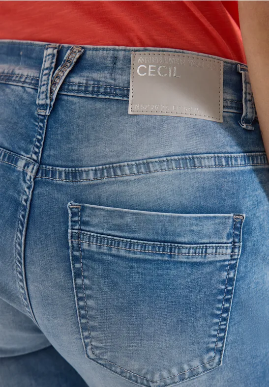 Tył osoby w niebieskich dżinsach z logo 'Cecil' i czerwonym topem.