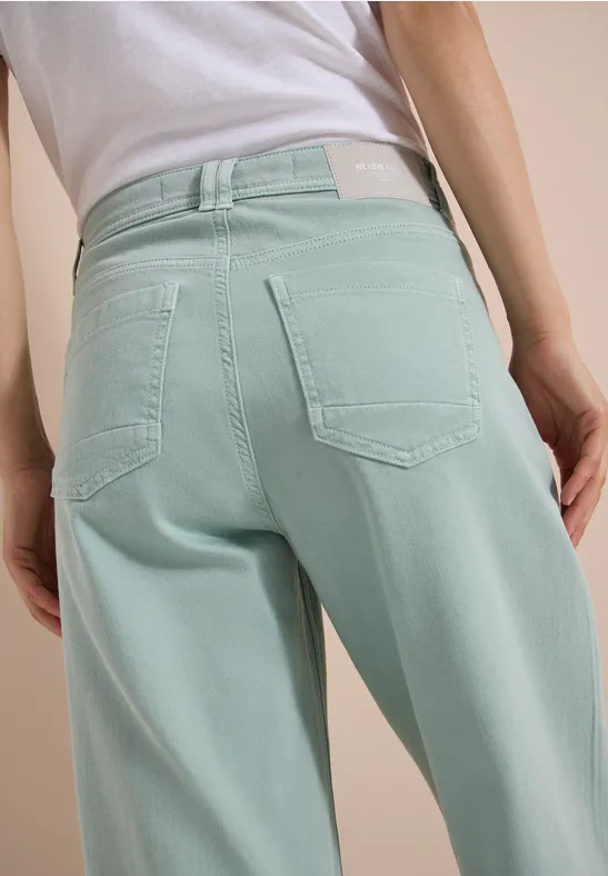 Achteraanzicht van een persoon in lichtturquoise, hoog model jeans.