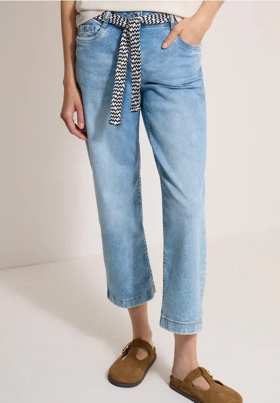 Jean bleu clair décontracté à ceinture zébrée, coupe cheville, porté avec des mocassins marron.