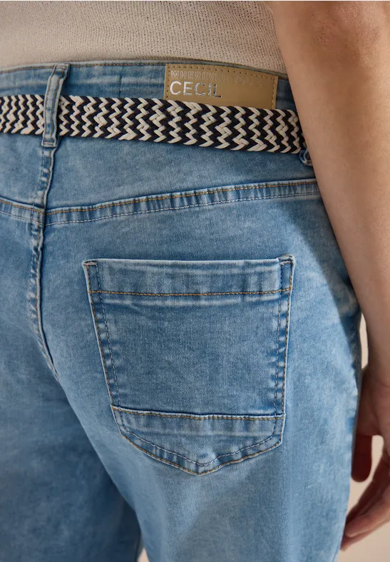 Vue arrière d’une personne en jean bleu avec ceinture tressée et étiquette en cuir visible.
