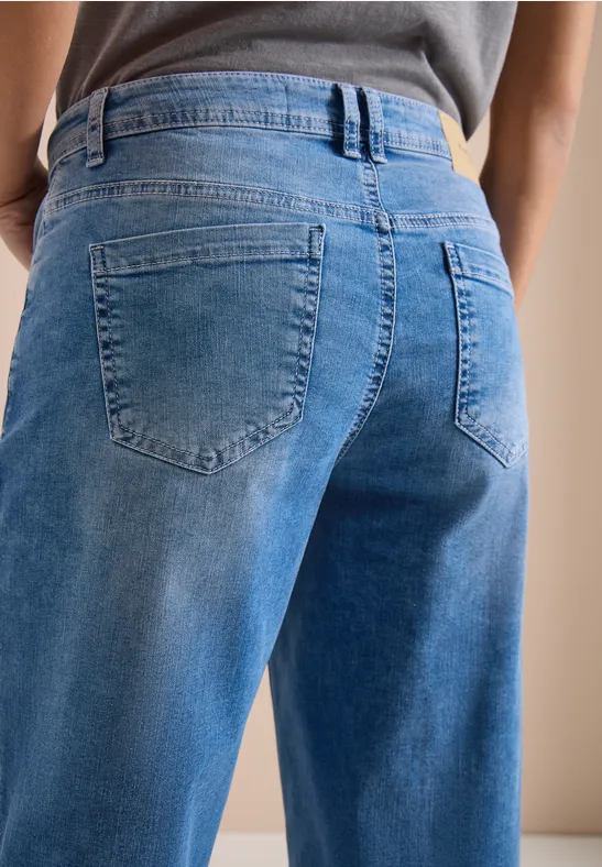 Person von hinten in lockeren blauen Jeans mit hoher Taille, sichtbare Gesäßtaschen und Bund.
