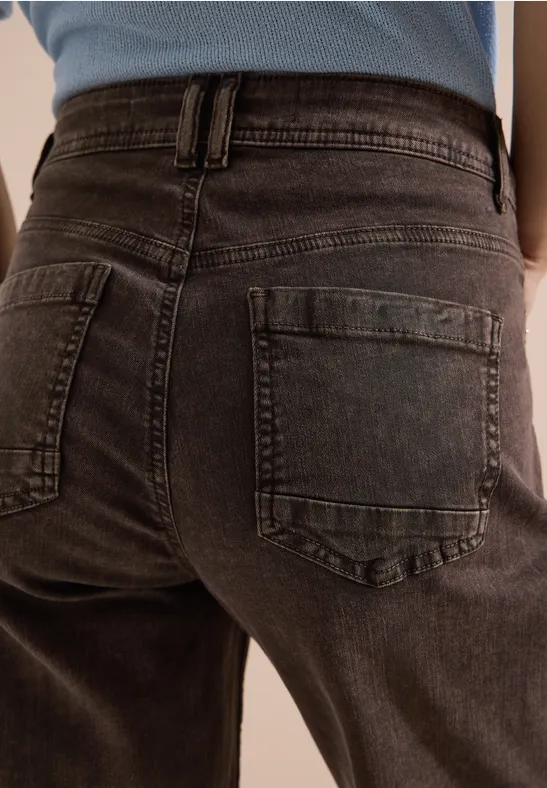 Rückenansicht einer Person in dunkelgrauen Jeans mit Gesäßstaschen.