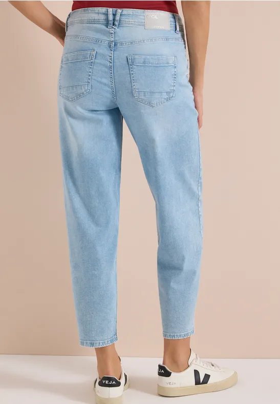 Rückansicht einer Person in hellblauen Jeans und weißen Sneakern.