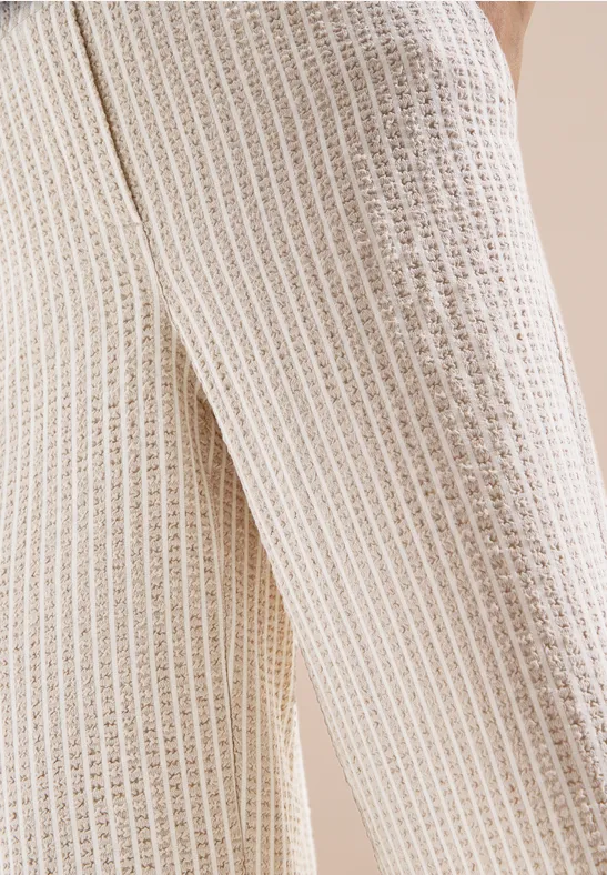 Nahaufnahme einer hellbeigen Strickhose mit Waffelstruktur