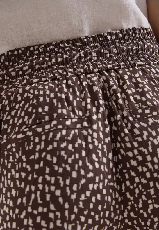 Braune, locker sitzende Hose mit elastischem Bund und unregelmäßigem weißen Punktemuster.