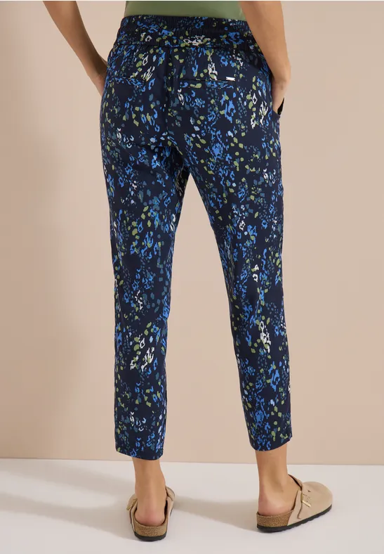 Knöchellange, dunkelblaue Stoffhose mit grün-blauem Blumenmuster und Taschen.