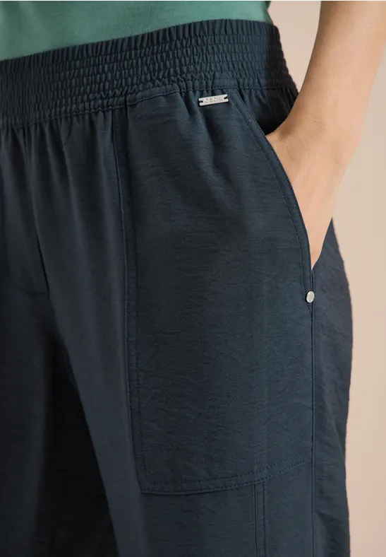 Zwarte, licht gestructureerde broek met elastische tailleband en zijzakken.