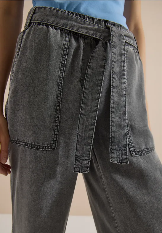 Jean noir ample à taille haute avec ceinture intégrée et grandes poches plaquées.