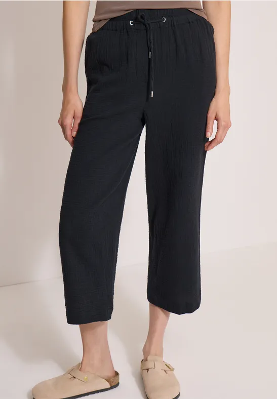 Schwarze, lässige Leinenhose mit Kordelzug und überschnittener Beinlänge, dazu bequeme, hellbeige Loafers