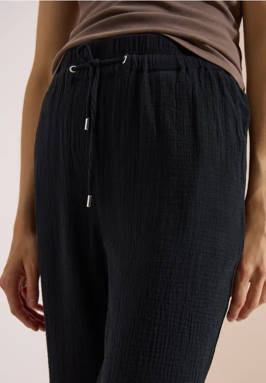 Schwarz strukturierte Hose mit Tunnelzug in Kombination mit braunem Topansatz.