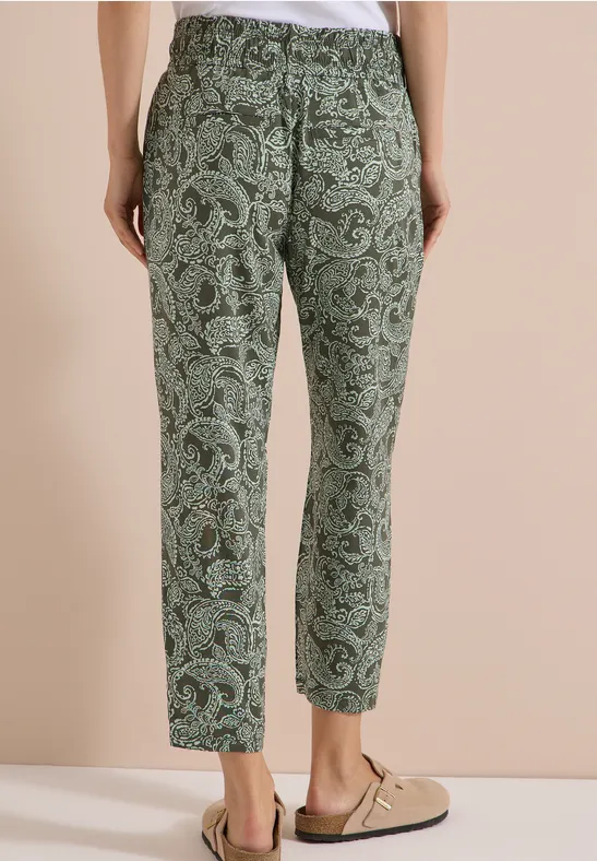 Grüne Stoffhose mit Paisley-Muster, lässiger Schnitt, getragen mit beigen Slippern.