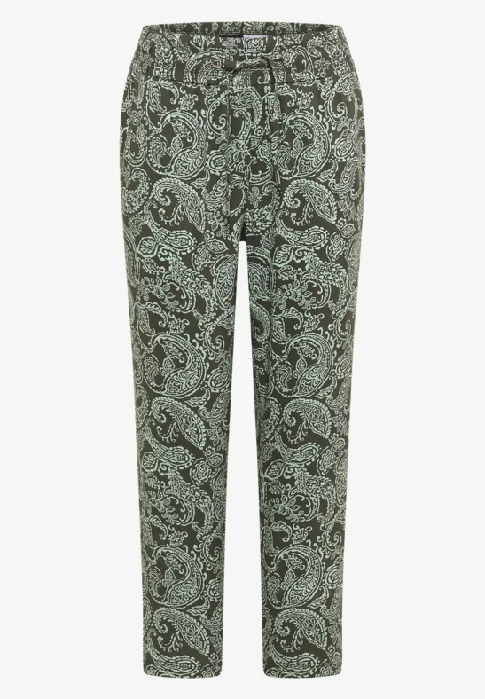 Grüne Stoffhose mit schwarzem Paisley-Muster und schmal zulaufendem Bein.