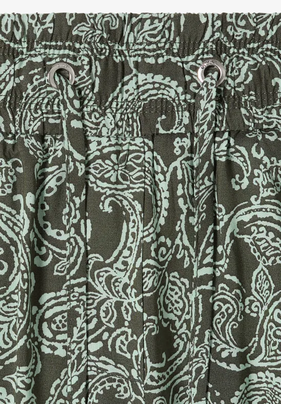 Nahaufnahme eines olivgrünen Stoffes mit hellblauem Paisley-Muster und Kordelzug in der Taille.