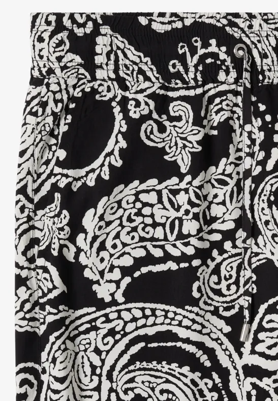 Close-up van zwart textiel met wit paisley- en bloemmotief.