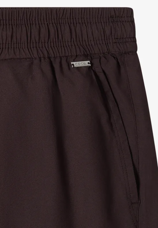 Nahaufnahme einer dunkelbraunen Hose mit Gummibund, Seitentasche und Metall-Label