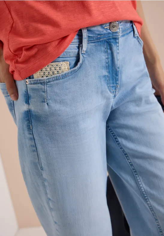 Frau trägt helle, locker sitzende Jeans mit gemustertem Einstecktuch in der Tasche und rotem Shirt.