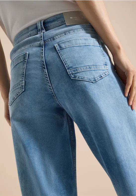 Detailaufnahme einer Person von hinten in hellblauen Jeans mit Rückentaschen.