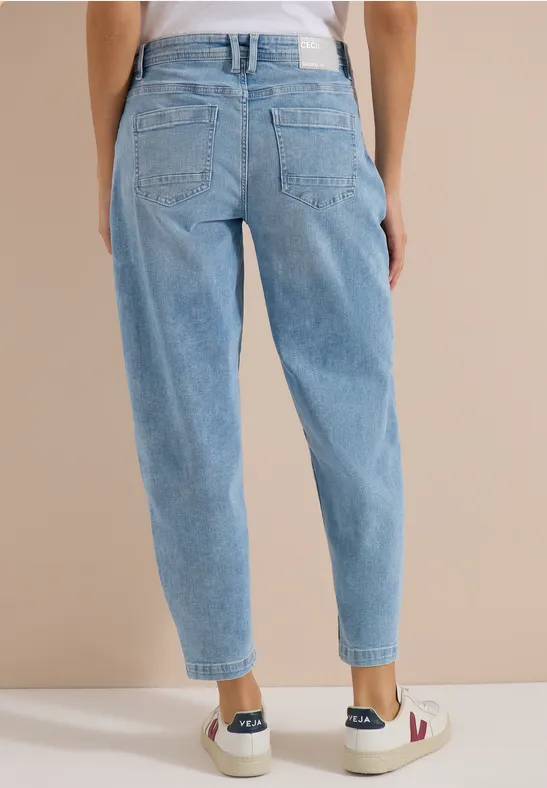 Rückansicht einer Person in hellblauen, locker sitzenden High-Waist-Jeans und weißen Sneakern.