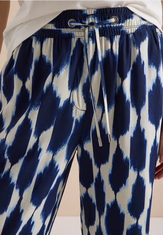 Locker geschnittene Hose mit blau-weißem abstraktem Muster und Tunnelzugbund.